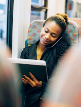 a business woman talks on the phone and works from a mobile tablet on an employee shuttle in NYC