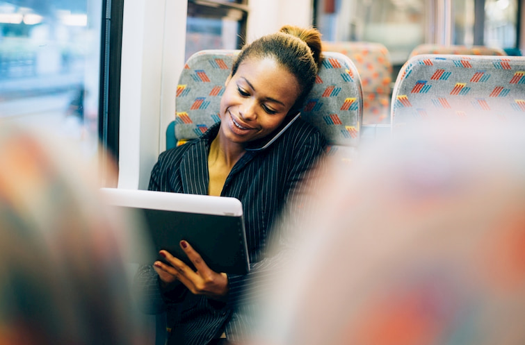 a woman takes a phone call and works from a mobile tablet while on an employee shuttle bus in New York City